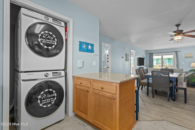 clothes washing area with ceiling fan, laundry area, light wood-type flooring, and stacked washing maching and dryer