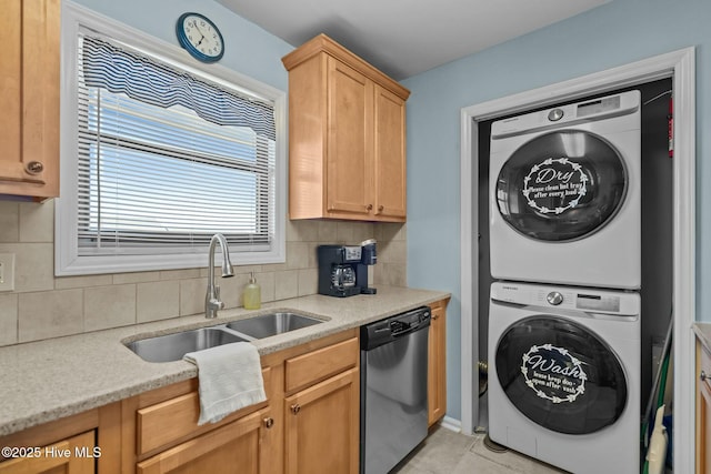 kitchen featuring tasteful backsplash, dishwasher, light tile patterned floors, stacked washing maching and dryer, and a sink