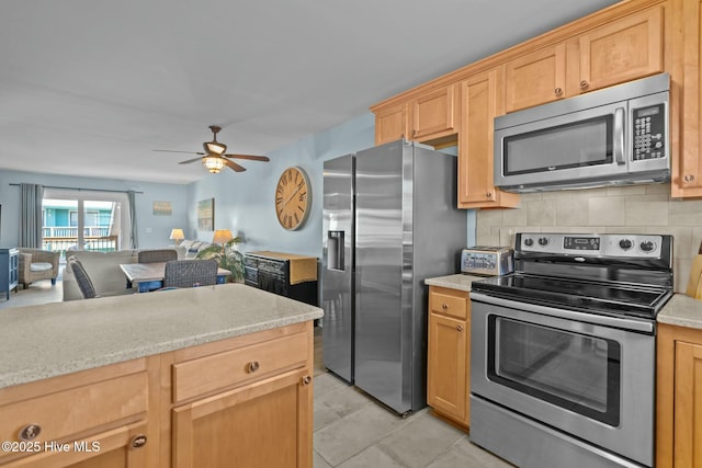 kitchen featuring a ceiling fan, light brown cabinets, backsplash, open floor plan, and appliances with stainless steel finishes