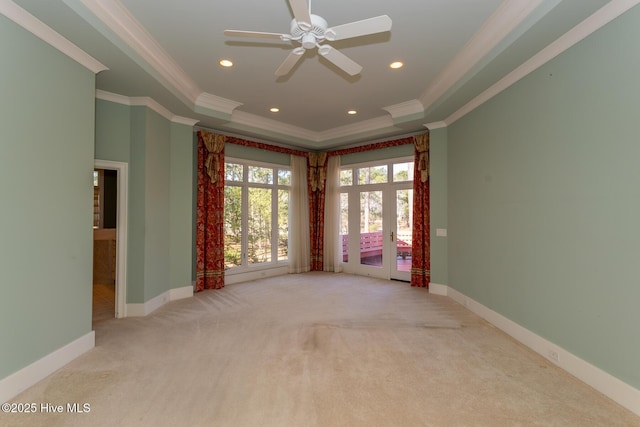 empty room featuring crown molding, a raised ceiling, baseboards, and carpet floors