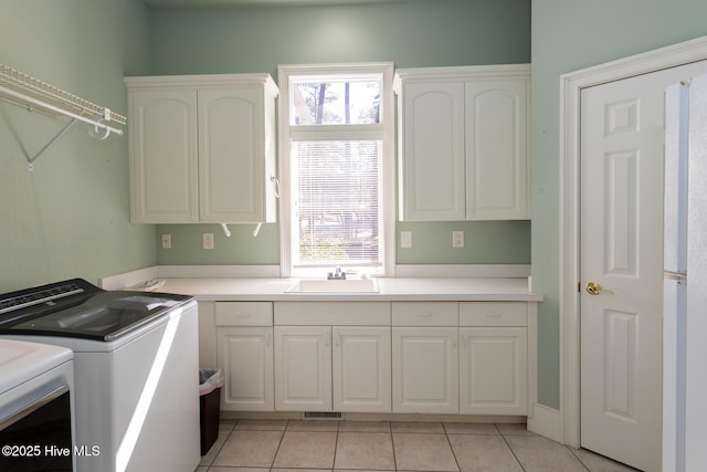 clothes washing area featuring a wealth of natural light, a sink, cabinet space, and separate washer and dryer