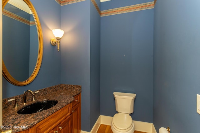 bathroom featuring baseboards, toilet, wood finished floors, and vanity