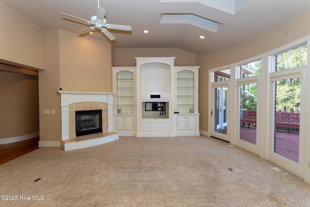 unfurnished living room featuring lofted ceiling with skylight, visible vents, recessed lighting, and carpet