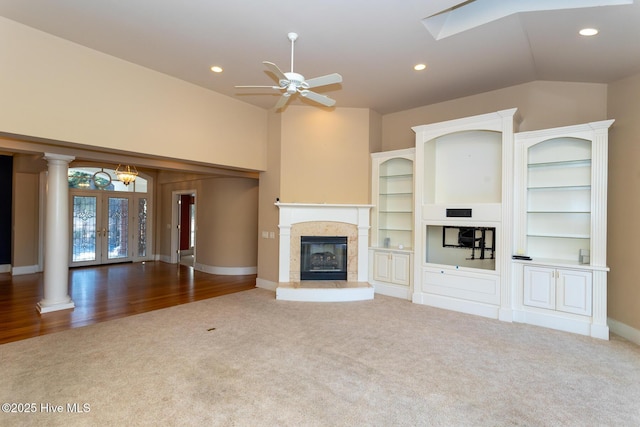 unfurnished living room featuring vaulted ceiling, decorative columns, carpet, and a premium fireplace