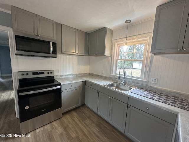 kitchen with a sink, appliances with stainless steel finishes, dark wood-style flooring, and gray cabinetry