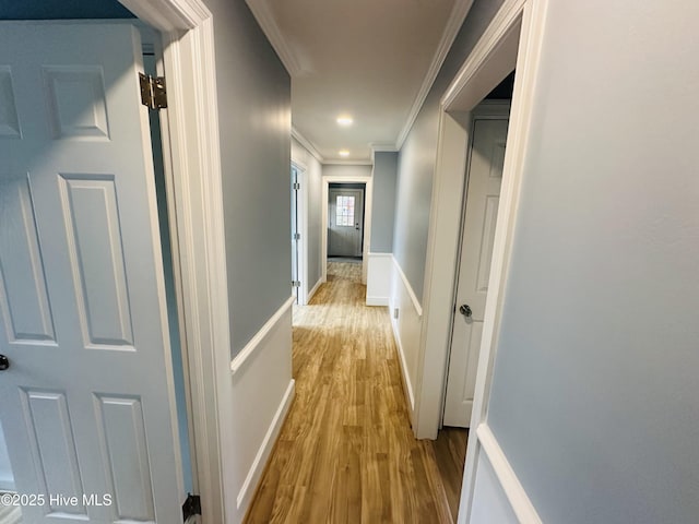 corridor featuring wood finished floors, baseboards, and ornamental molding