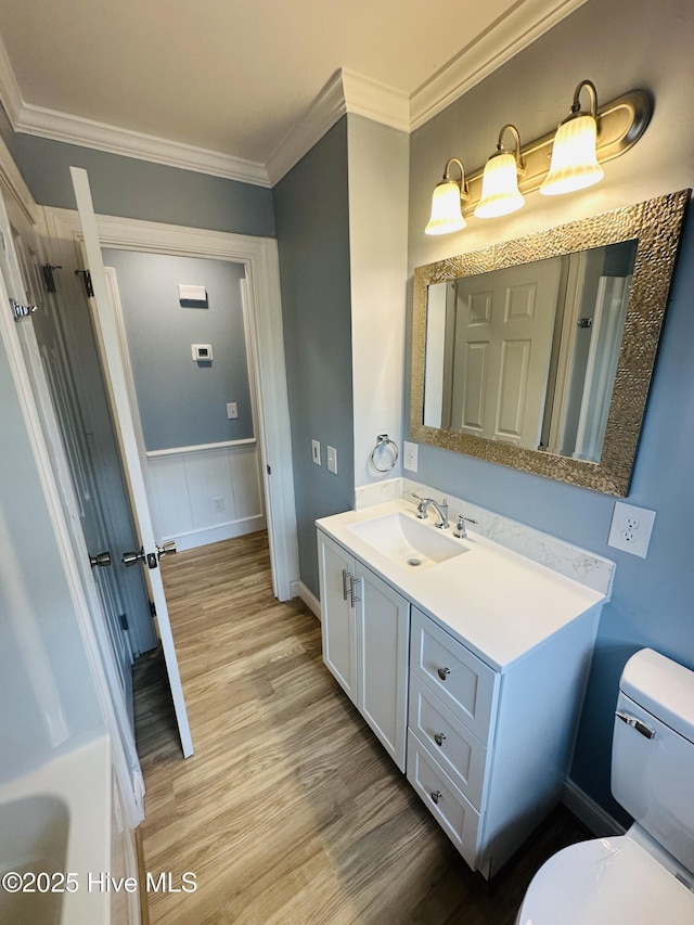 bathroom with vanity, toilet, wood finished floors, and ornamental molding