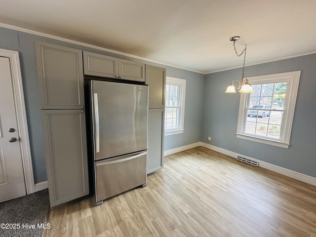 kitchen featuring visible vents, a healthy amount of sunlight, crown molding, gray cabinets, and freestanding refrigerator