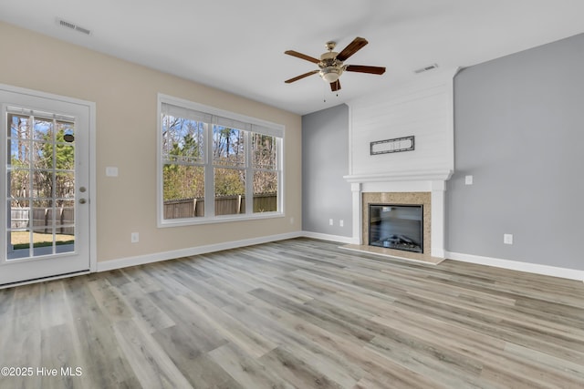 unfurnished living room featuring a healthy amount of sunlight, visible vents, and a premium fireplace