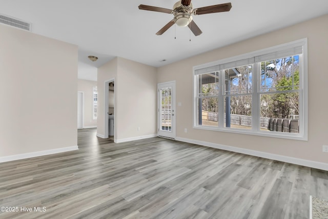 interior space featuring wood finished floors, baseboards, visible vents, and ceiling fan