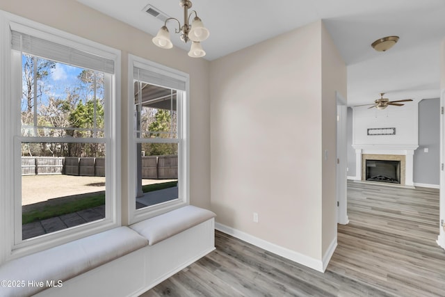 dining room with wood finished floors, a fireplace, visible vents, and baseboards