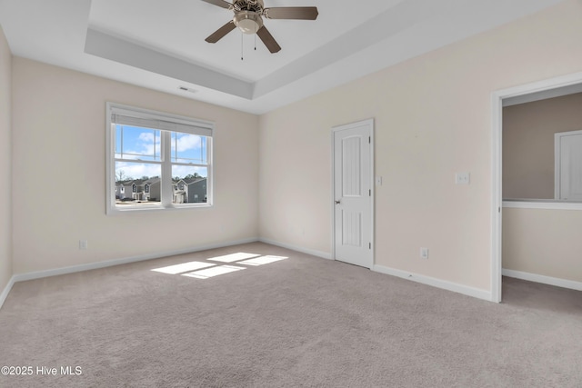 unfurnished bedroom with carpet flooring, visible vents, baseboards, and a tray ceiling