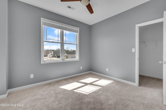 carpeted spare room featuring a ceiling fan, visible vents, and baseboards