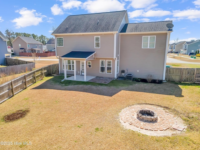 back of house with a fire pit, central AC, a fenced backyard, a yard, and a patio area