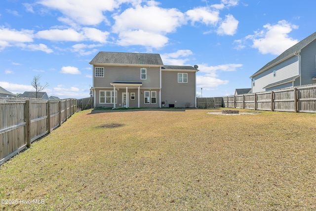 back of property with a fenced backyard and a yard