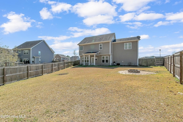 rear view of house featuring a yard, a fenced backyard, and an outdoor fire pit