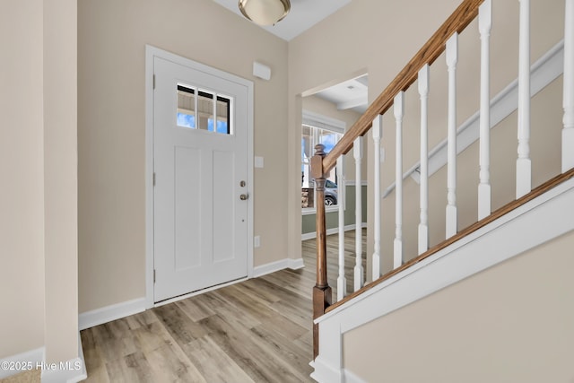 foyer with stairway, wood finished floors, and baseboards