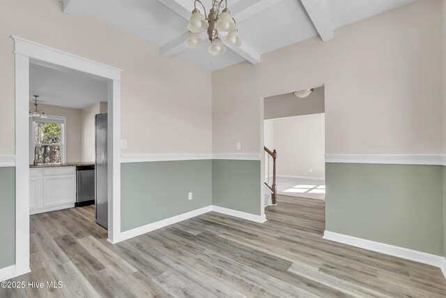 empty room featuring stairway, baseboards, light wood finished floors, beamed ceiling, and a chandelier