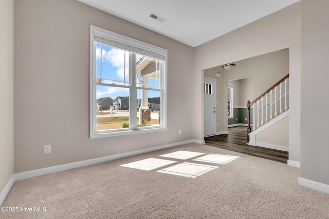 spare room with stairs, baseboards, visible vents, and dark carpet