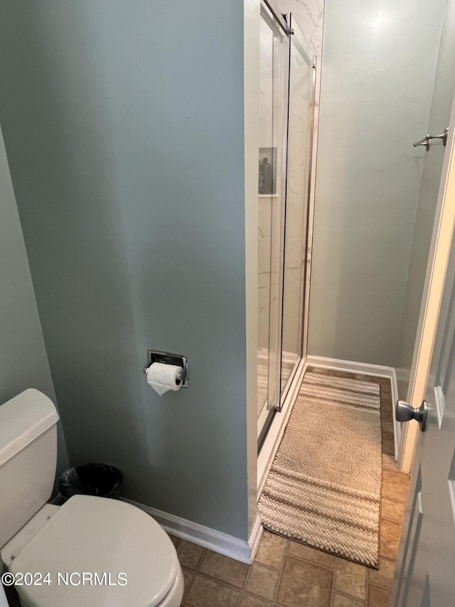 full bathroom featuring a shower stall, toilet, and baseboards