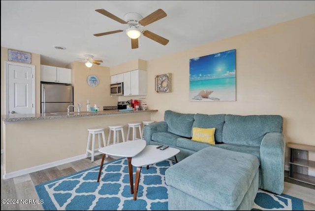 living area featuring ceiling fan, visible vents, baseboards, and wood finished floors