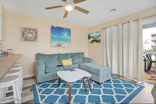 living room with visible vents, baseboards, a ceiling fan, and wood finished floors