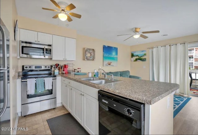 kitchen with a sink, a peninsula, appliances with stainless steel finishes, white cabinets, and ceiling fan