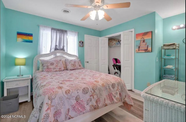 bedroom with visible vents, a ceiling fan, wood finished floors, a closet, and baseboards