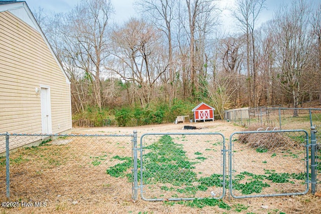 view of yard featuring a storage shed, fence, an outdoor structure, and a gate