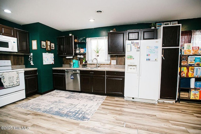 kitchen featuring light wood finished floors, visible vents, light countertops, white appliances, and a sink