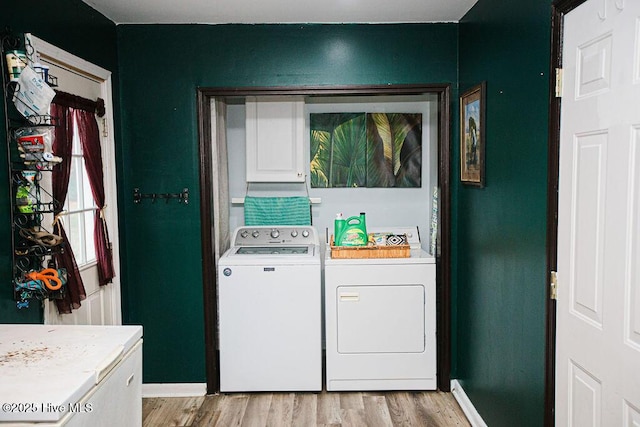 washroom with light wood-style flooring, cabinet space, baseboards, and washing machine and clothes dryer