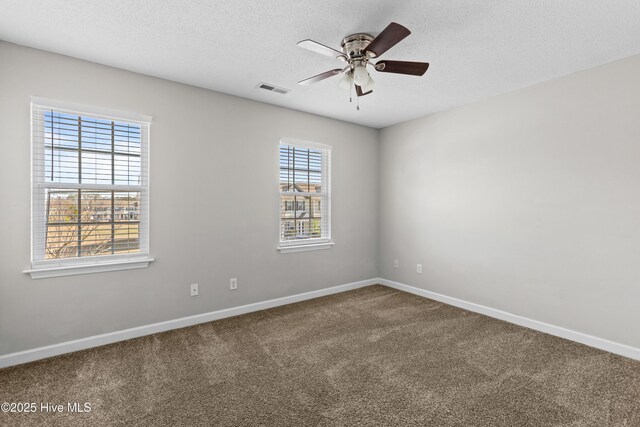 empty room with visible vents, a textured ceiling, carpet, baseboards, and ceiling fan