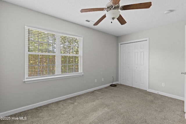 unfurnished bedroom with a ceiling fan, baseboards, visible vents, carpet floors, and a closet