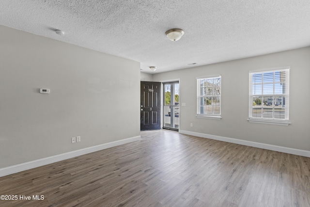 empty room featuring baseboards, a textured ceiling, and wood finished floors