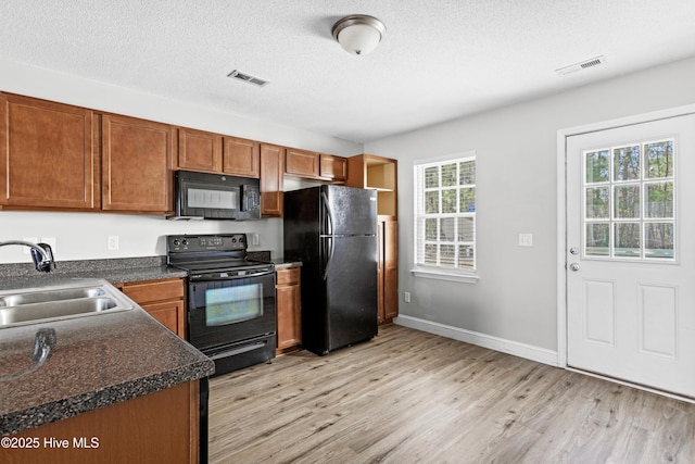 kitchen featuring a sink, visible vents, black appliances, and light wood finished floors