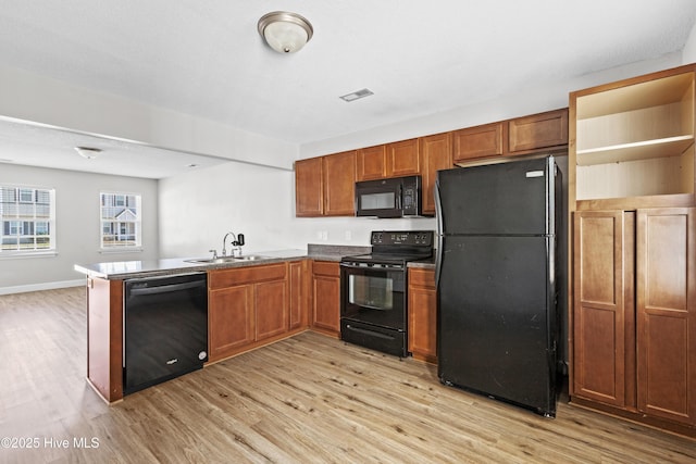 kitchen featuring visible vents, black appliances, a sink, light wood-style floors, and a peninsula