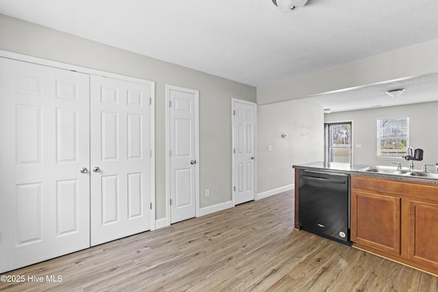 kitchen with baseboards, brown cabinets, a sink, dishwasher, and light wood-type flooring