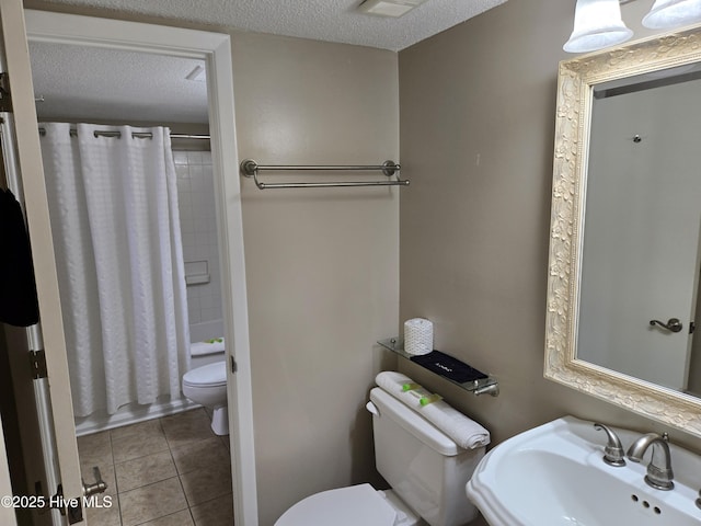 bathroom featuring tile patterned flooring, a sink, toilet, a textured ceiling, and shower / bathtub combination with curtain