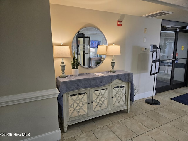 corridor with tile patterned floors, baseboards, and visible vents