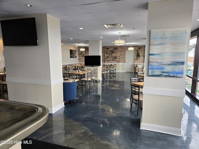 dining space featuring visible vents, brick wall, baseboards, marble finish floor, and a paneled ceiling