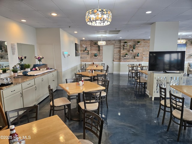 dining area with recessed lighting, a drop ceiling, and concrete flooring