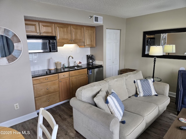 kitchen featuring dark countertops, visible vents, dark wood finished floors, black appliances, and a sink