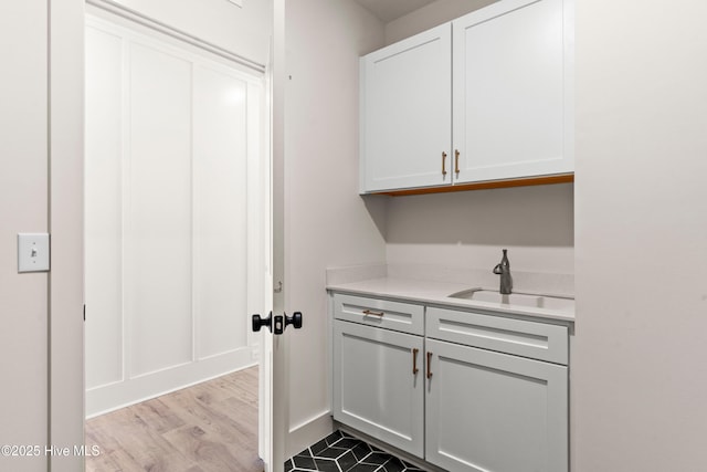 clothes washing area featuring a sink and light wood-style floors