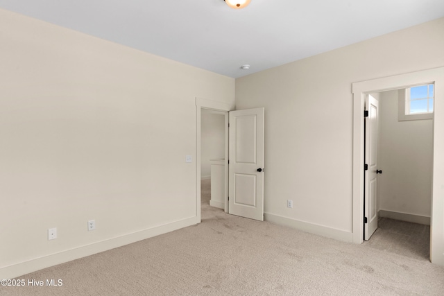 unfurnished bedroom featuring baseboards, a walk in closet, and carpet