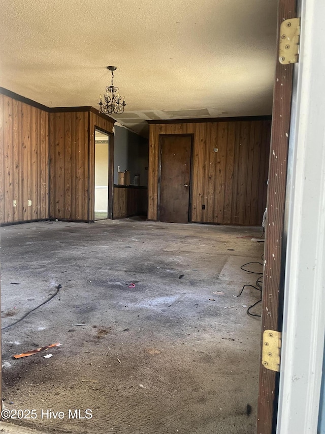 unfurnished room featuring wooden walls, crown molding, and a textured ceiling