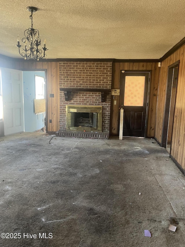 unfurnished living room featuring wooden walls, ornamental molding, a fireplace, and a textured ceiling