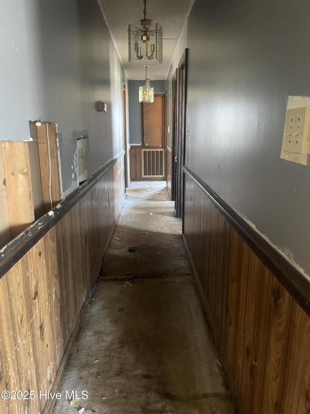 corridor with a wainscoted wall, an upstairs landing, a notable chandelier, visible vents, and wood walls