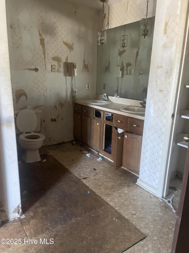 bathroom with a sink, toilet, and double vanity