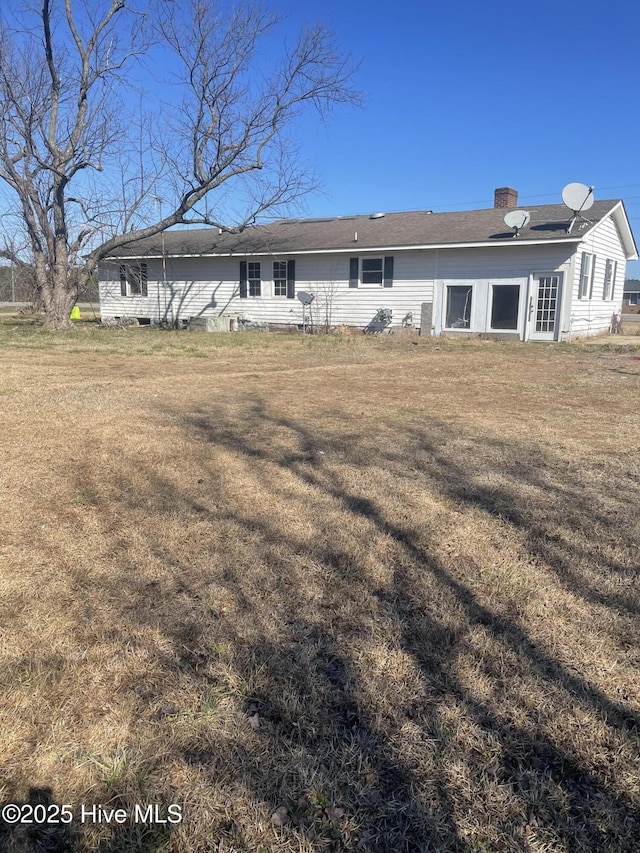 rear view of property featuring a lawn and a chimney