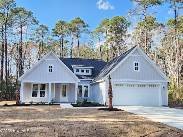 modern inspired farmhouse with covered porch, a garage, driveway, and roof with shingles